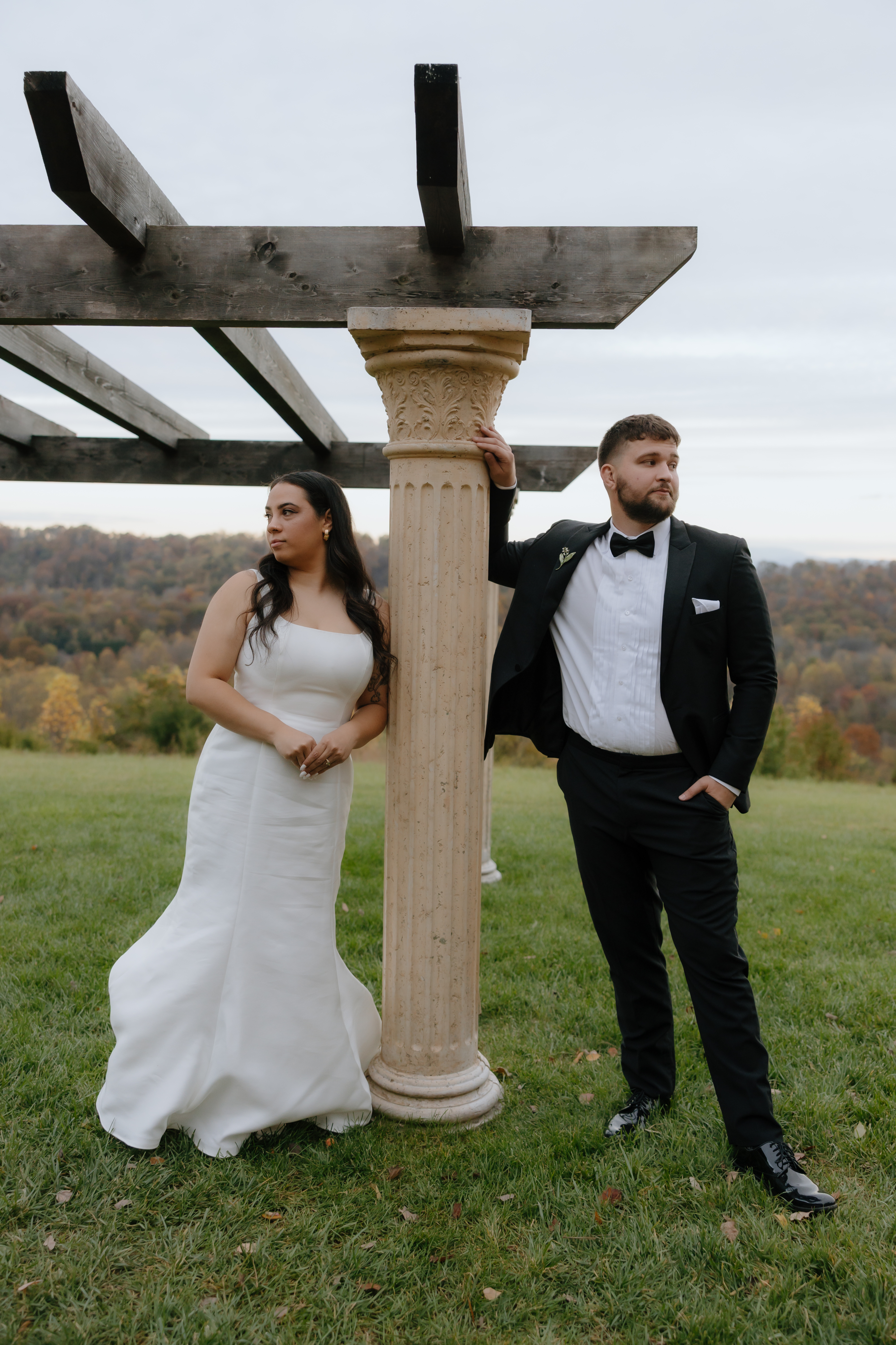 Bride and groom posing beside stone columns on their wedding day.