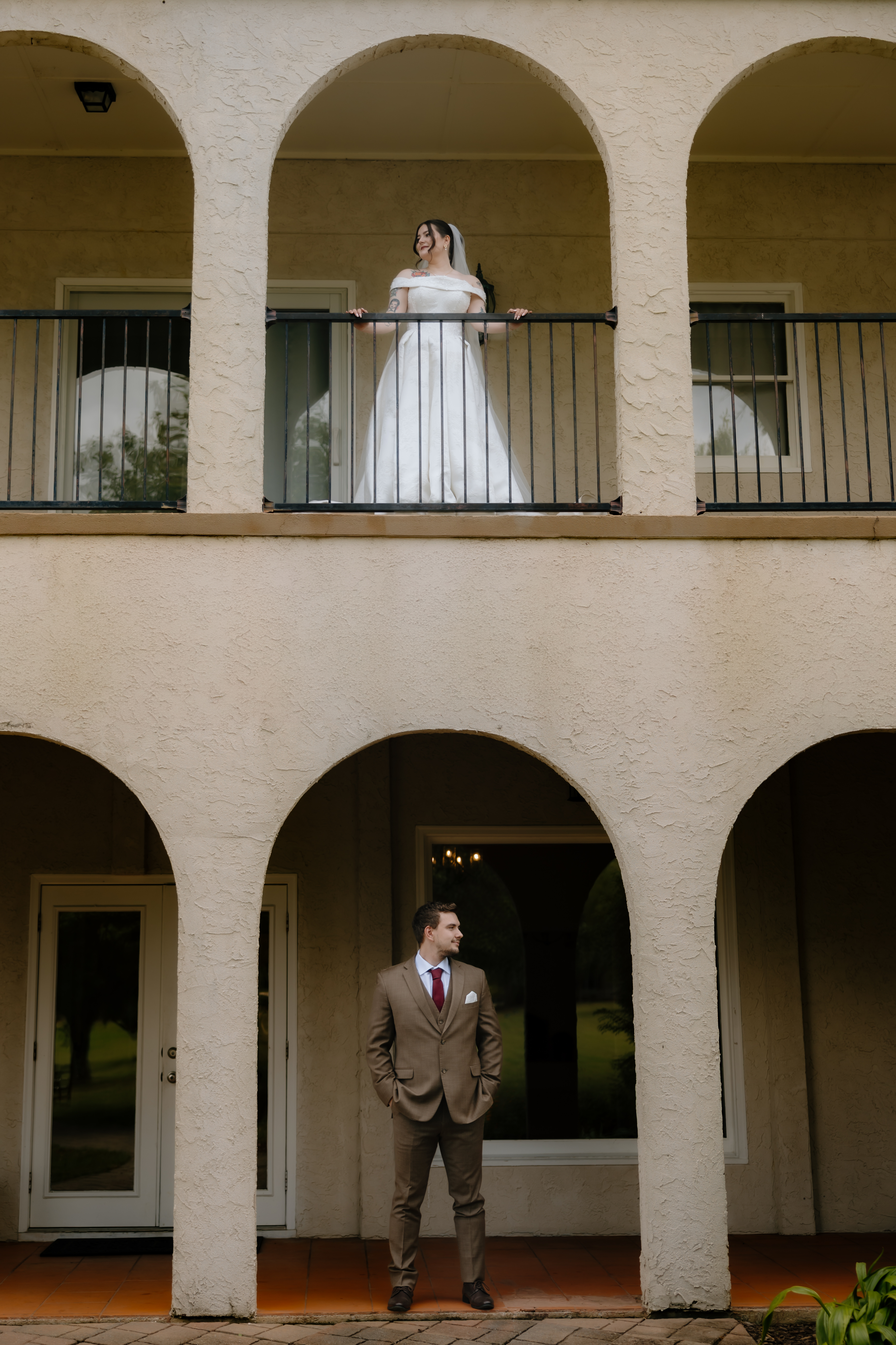 Bride and groom standing beneath arched balconies
